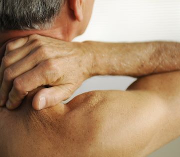 man massaging his neck and shoulder to relive pain